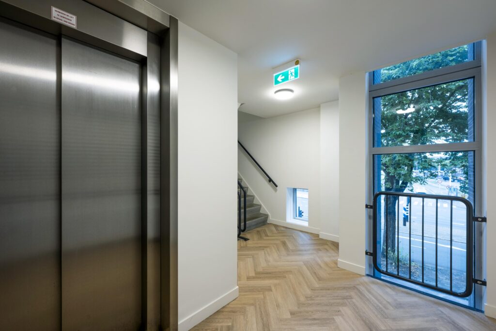 Moderne lichtinval in een trappenhuis met lift en groot raam aan de Prins Hendrikkade.